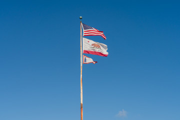 View of Old Rusted Flag Pole With Three Flags