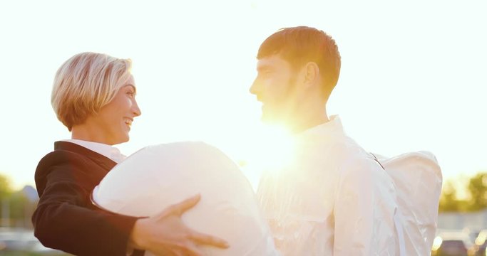 Young Caucasian beautiful and happy woman taking off head armor of astronaut who coming back homa on Earth after space travel and hugging a handsome man. Wife meeting her husband.