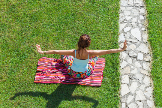 adult woman practice yoga outdoor in her backyard on grass summer day shot from above