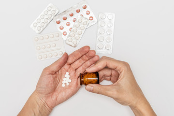 Obraz premium Hands holding a glass bottle and pills on a palm, patient taking pills and following doctor prescription