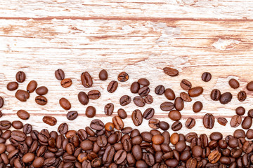 roasted coffee beans scattered on a background with a wood texture. coffee mania.close up.