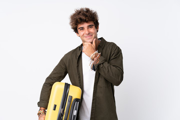 Young Traveler man holding a suitcase over isolated white background laughing