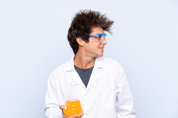 Young scientific man over isolated blue background looking to the side