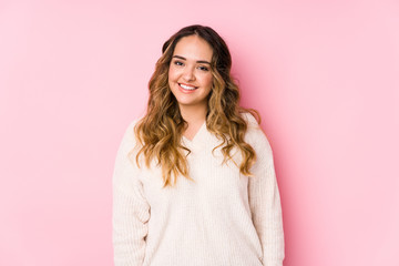 Young curvy woman posing in a pink background isolated happy, smiling and cheerful.