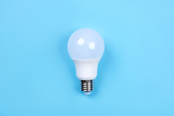LED bulb on blue background. Saving energy concept. Ftat lay. Top view.