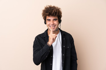 Fototapeta na wymiar Telemarketer man working with a headset over isolated background doing silence gesture