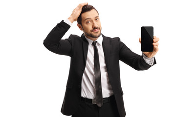 Unhappy businessman holding his head and showing a mobile phone