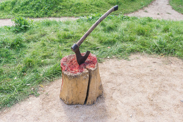 Axe of executioner from middle Ages. Beheading on medieval festival. Victim's blood on wooden stump. Bloody wood block at place of execution of defendant