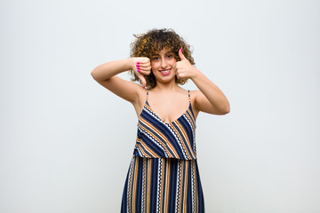 young pretty woman feeling confused, clueless and unsure, weighting the good and bad in different...