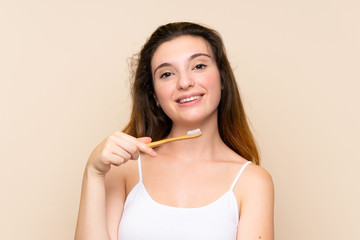 Young brunette girl brushing her teeth.over isolated background
