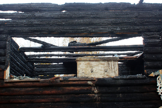 Country wooden house after a fire. Burnt walls, charred logs. The devastating effects of a fire.