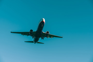 Plane arrival landing at airport. Majestic slowly drifting passanger airplane against blue sky.