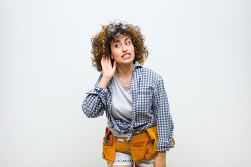 young housekeeper woman looking serious and curious, listening, trying to hear a secret...
