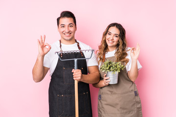 Young couple gardener isolated cheerful and confident showing ok gesture.