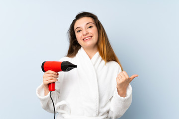 Young woman in a bathrobe with hair hairdryer pointing to the side to present a product