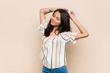 Young cute chinese teenager Young blonde woman wearing a coat against a pink background stretching arms, relaxed position.