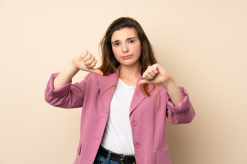 Young brunette girl with blazer over isolated background showing thumb down