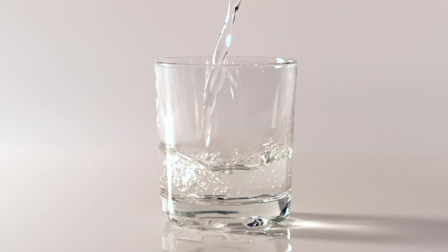 Pouring fresh pure water into a clear glass on white background. Health and diet concept. Water filling into transparent glass