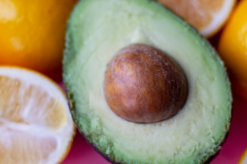 Flat lay composition with yellow lemons and green avocado, and space for text on color pink background.