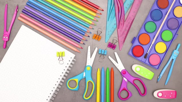 Colorful school and art supplies and opened notebook appear on grey background - Stop motion 