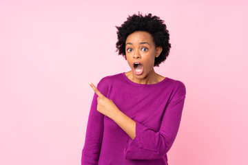 African american woman over isolated pink background surprised and pointing side