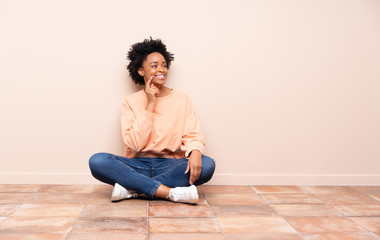 African american woman sitting on the floor thinking an idea while looking up
