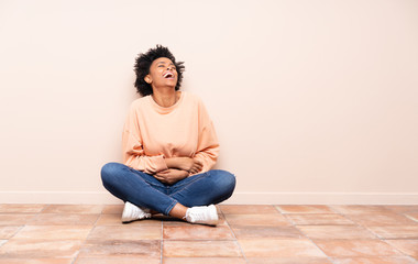 African american woman sitting on the floor smiling a lot