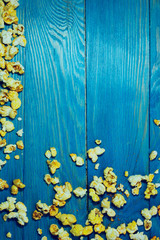 Yellow caramelized popcorn on a blue wooden background.  Fast food, junk food. Abstract colorful food background.