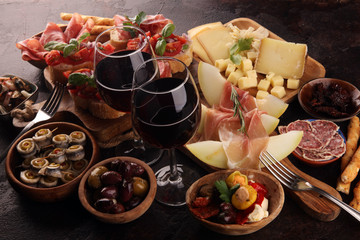 Italian antipasti wine snacks set. Cheese variety, Mediterranean olives, seafood salad, Prosciutto di Parma, tomatoes, anchovy and wine in glasses