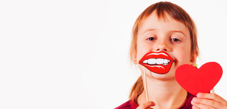 Valentines day and child carnival concept. Funny image of cute little girl with fake lips and red heart.