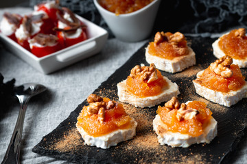 Still life of Goat roll cheese with jam and walnuts with cherry tomatoes stuffed with cheese and anchovies. Front view