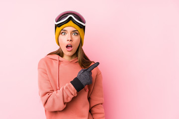 Young caucasian woman wearing a ski clothes isolated pointing to the side