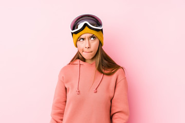 Young caucasian woman wearing a ski clothes isolated confused, feels doubtful and unsure.