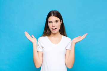 young pretty woman feeling happy, excited, surprised or shocked, smiling and astonished at...