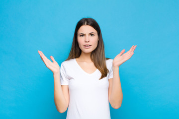 young pretty woman looking shocked and astonished, with jaw dropped in surprise when realizing...