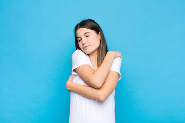 young pretty woman feeling in love, smiling, cuddling and hugging self, staying single, being...