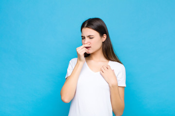 young pretty woman feeling disgusted, holding nose to avoid smelling a foul and unpleasant stench...