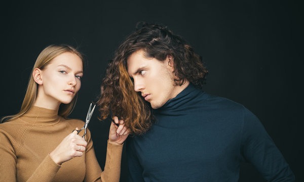 Fototapeta Hairdresser girl going to cut off long wavy bleached dry hair of customer man. Man hair style, wellness and fashion. Female with scissors going to do amazing man haircut. Hair salon concept.