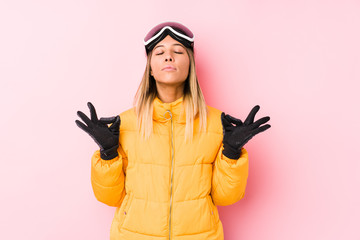 Young caucasian woman wearing a ski clothes in a pink background relaxes after hard working day,...