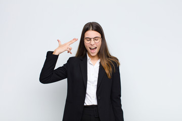 young businesswoman looking unhappy and stressed, suicide gesture making gun sign with hand,...