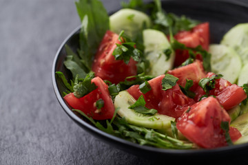 Salad with Tomatoes, Cucumber and Rocket on stone Background. Healthy Snack Idea. Close up.