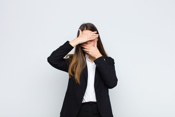 young businesswoman covering face with both hands saying no to the camera! refusing pictures or...