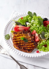Grilled pork steak with fresh salad. White background
