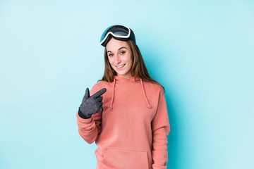 Young caucasian woman wearing a ski clothes isolated pointing with finger at you as if inviting come closer.