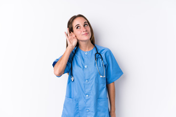 Young nurse woman isolated trying to listening a gossip.