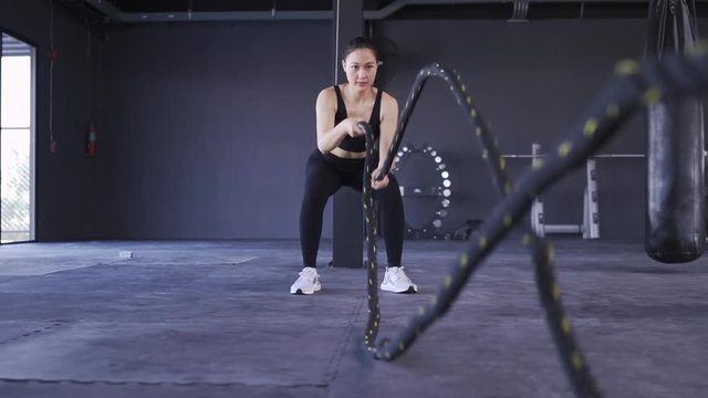 Woman exercise with Battle ropes during  in cross fitness gym healthy lifestyle muscle builder, Athletic sport woman training endurance strong focus bicep workout. HD Slow motion  Footage cinematic 