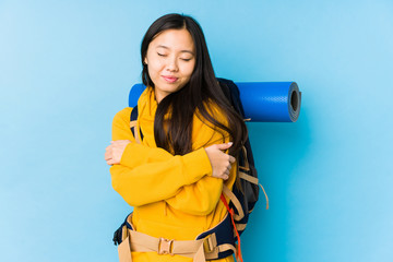 Young chinese backpacker woman isolated hugs, smiling carefree and happy.