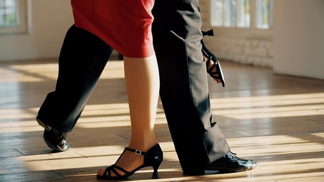 close-up of the legs of a man and a woman dancing a pair of ballroom dance in the room. Dance moves of the tango, Latinos, the Paso Doble. Gait.