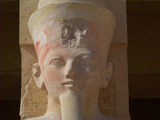 Closeup on craved statue of Pharaoh Hatshepsut, her face in focus with hints of original paint. 