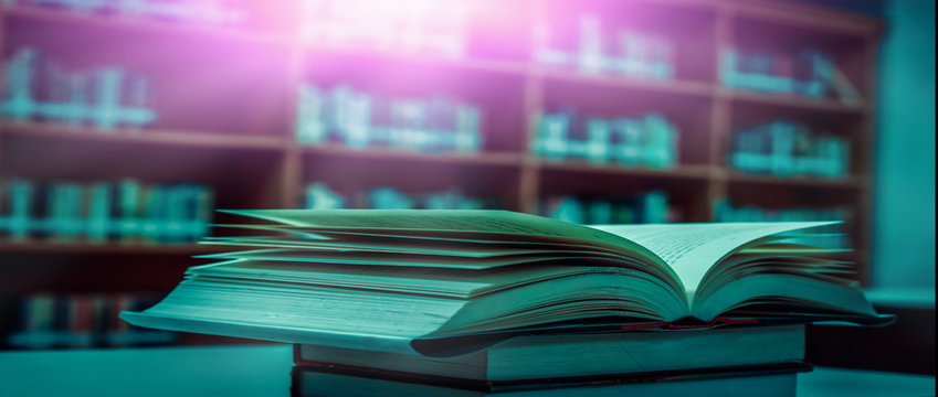 Stack of books in the library and blur bookshelf background	